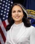 Official portrait of Tulsi Gabbard in a white suit with U.S. flag in the background.